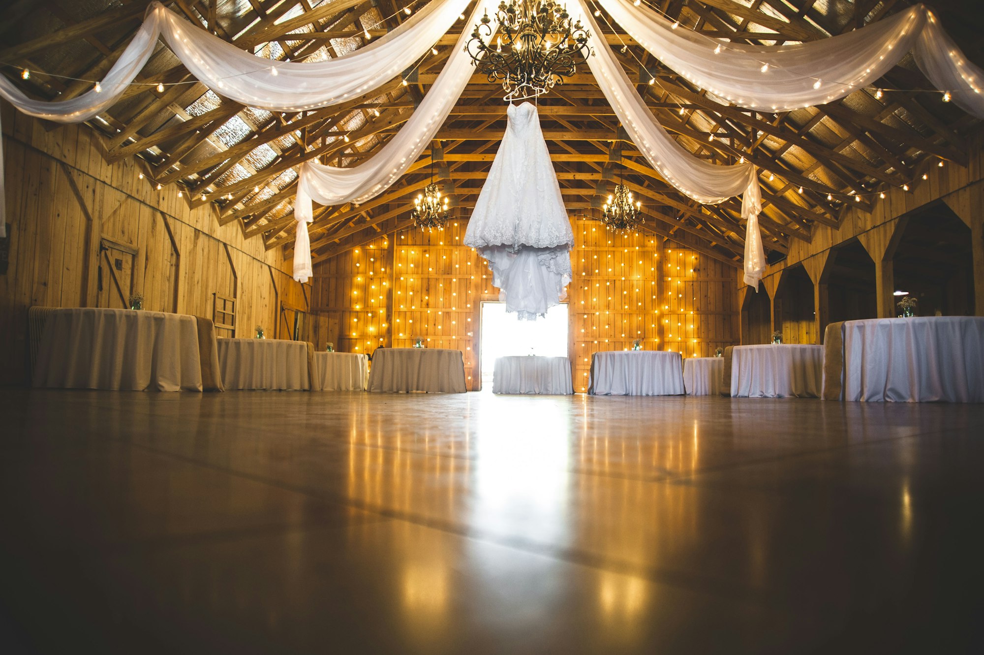 Bare round tables and folded linen in an empty reception room the morning before a wedding