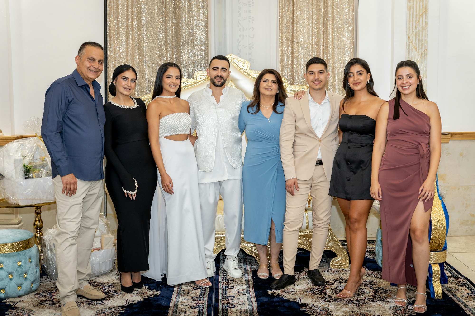 A wedding party and family lined up shoulder to shoulder for a group photograph indoors