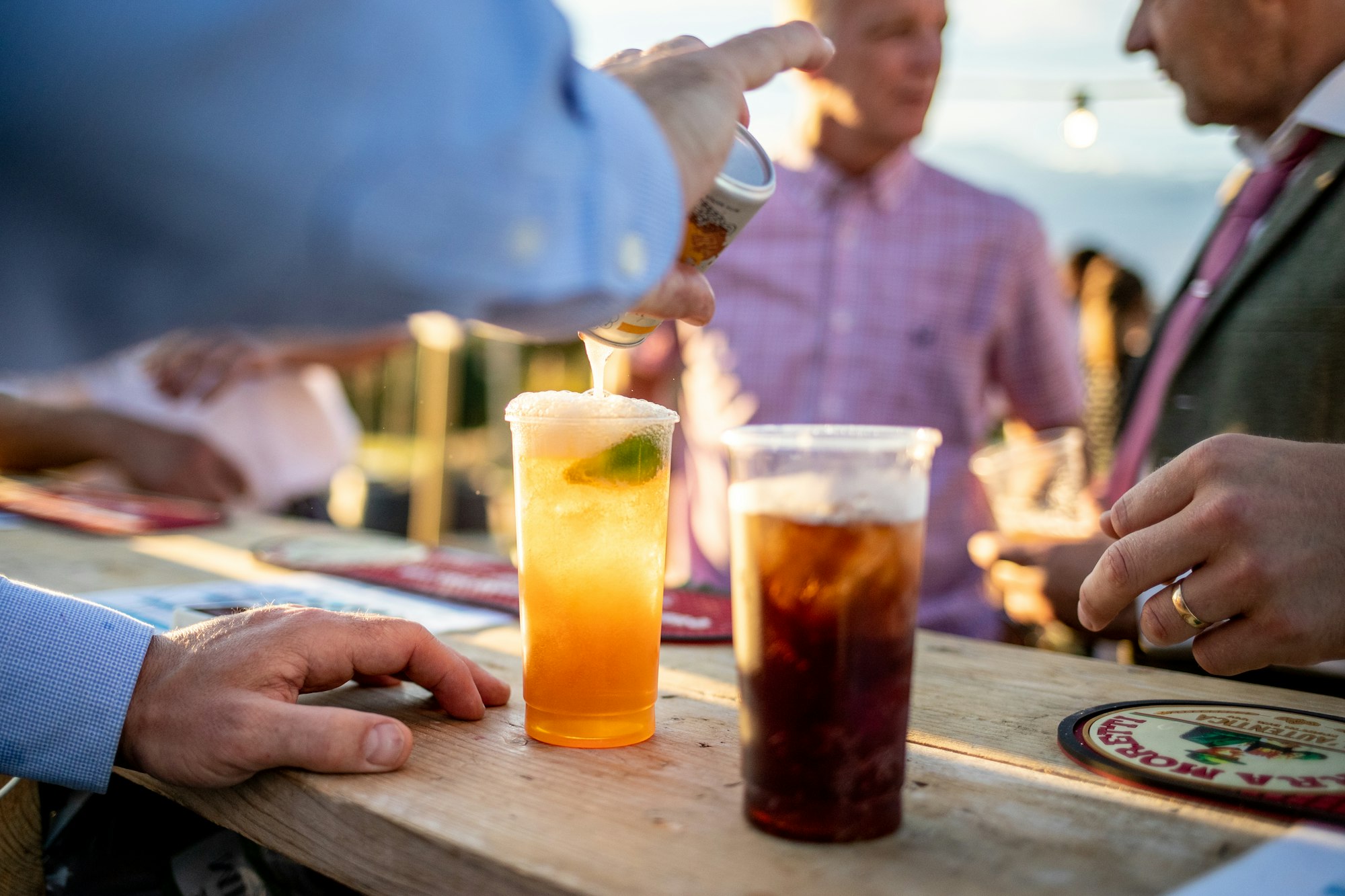 Guests gathered around a table with drinks during the cocktail hour between ceremony and reception