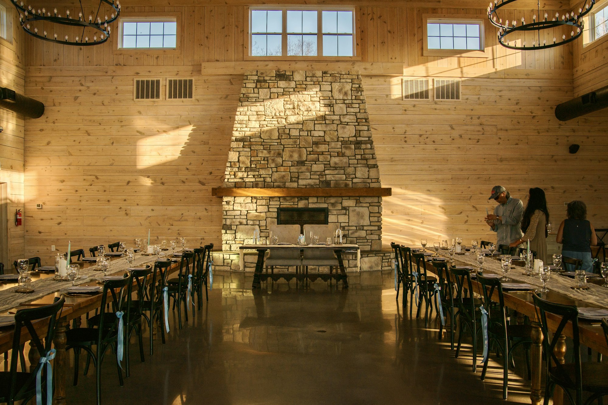 A long banquet table laid and lit in a stone-walled hall before any guests arrive