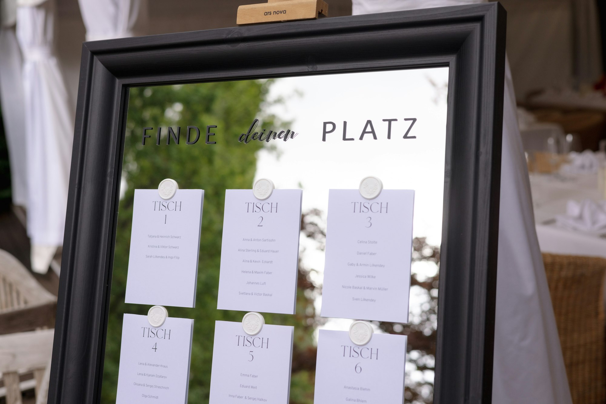 A wedding seating chart written on a mirror, guests listed by table number