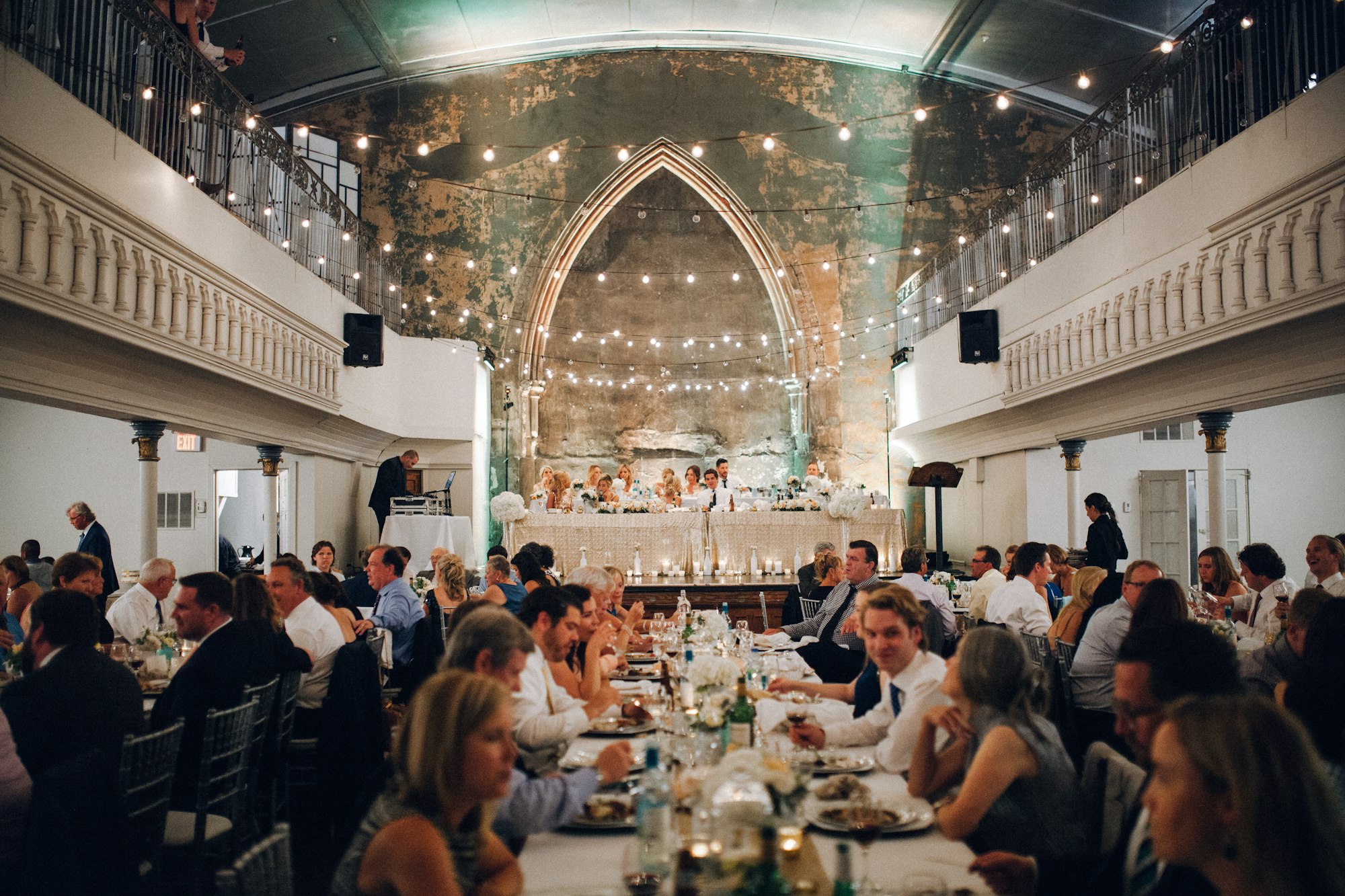 Guests seated at a long reception table mid-meal, plates and glasses in front of them